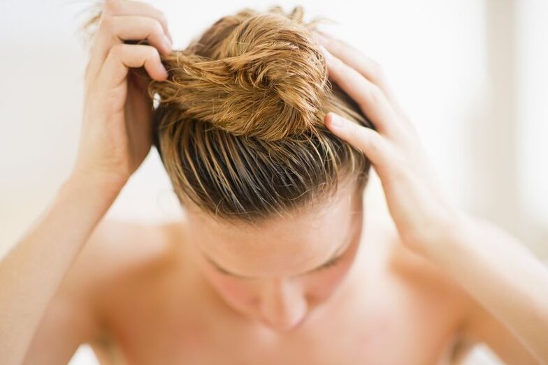 La ragazza si è applicata un prodotto anticalvizie sui capelli.